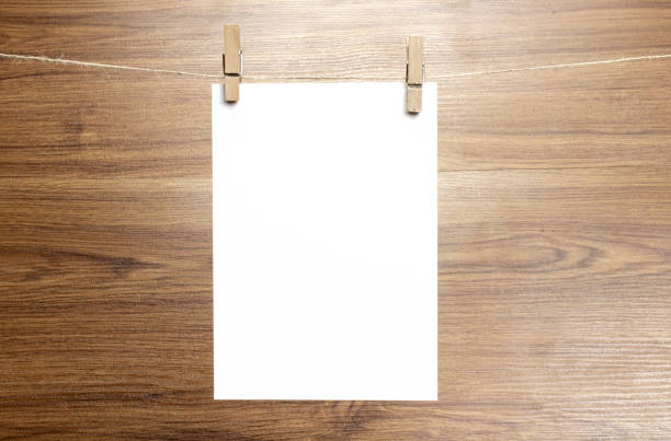 istock Empty paper sheet frame that hang on a rope with clothespins and on wooden background. Blank cards on rope. Mockup template for memories backdrop, photos, social media etc. 1210375931