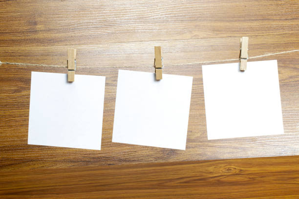 istock Empty paper sheets for notes, frames that hang on a rope with clothespins on wooden background. Blank cards on rope. Mockup template for memories backdrop, photos, social media etc. 1210375967