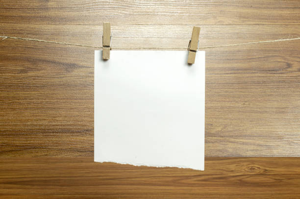 istock Empty torned paper sheets for notes, frames that hang on a rope with clothespins and isolated on white. Blank cards on rope mockup. 1210375997