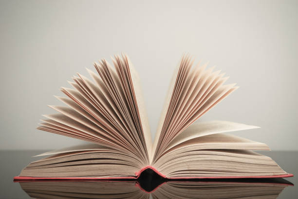 istock Beautiful open book on a gray and glass table background. 1210377737
