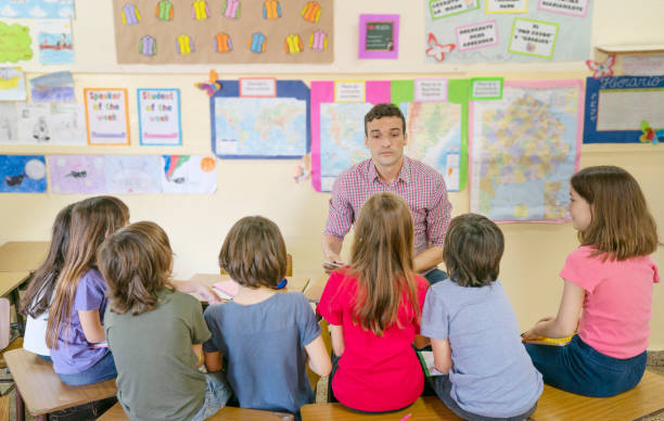 Teacher talking with a small group of children at school about values stock photo