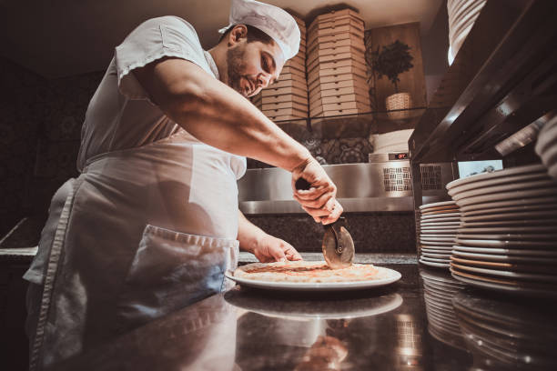 istock Chef is cutting freshly prepared pizza 1210377854