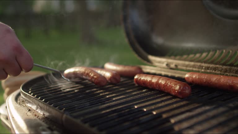 Delicious hot dogs getting rotated on the grill