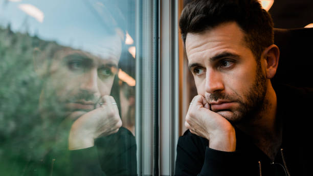 Young bearded man traveling by train in late afternoon