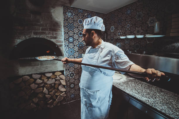istock Chef is putting pizza to the oven 1210378344