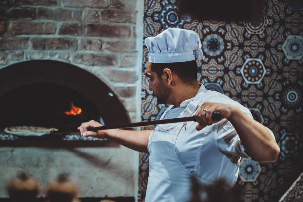 istock Chef is putting pizza to the oven 1210378372
