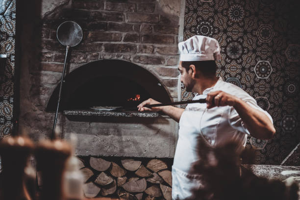 istock Chef is putting pizza to the oven 1210379452