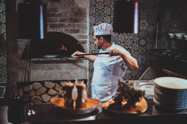 istock Chef is putting pizza to the oven 1210379473