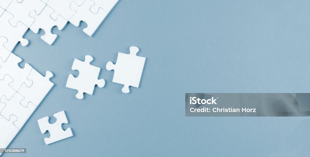 top view of white blank unfinished jigsaw puzzle top view of white blank unfinished jigsaw puzzle on blue background, completing a task or solving a problem concept Jigsaw Piece Stock Photo