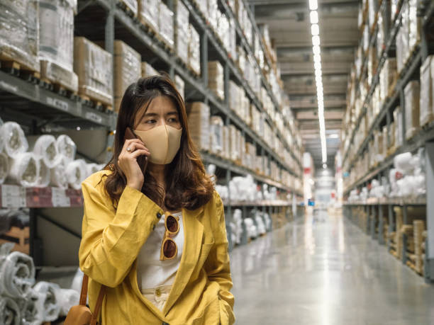 istock Woman wearing a face mask and using smartphone in warehouse. 1210394045