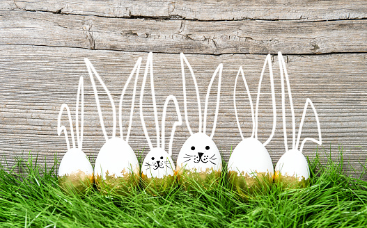 Creative Easter decoration. Easter eggs in green grass on wooden background