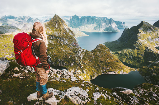 Traveler woman with red backpack hiking in mountains of Norway Traveling healthy lifestyle adventure concept summer active vacations outdoor