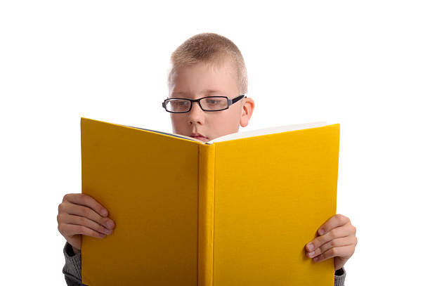 istock boy with glasses reading a big yellow book 121039724