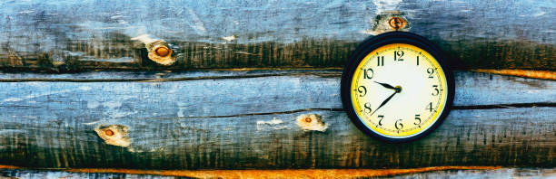 Old clock hanging on a wall of logs. Panorama.