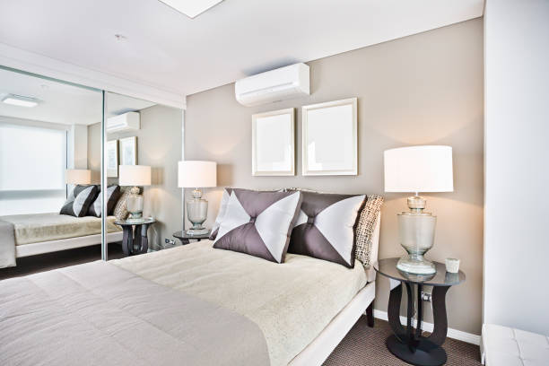 Comfortable bed and pillows with lamps in bedroom.
