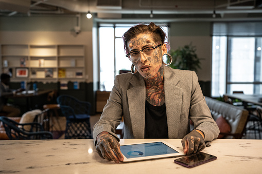 Portrait of tattooed businesswoman working with digital tablet at lobby office