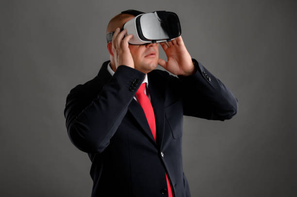 istock Businessman dressed in black suit wearing virtual reality VR glasses 1210409875