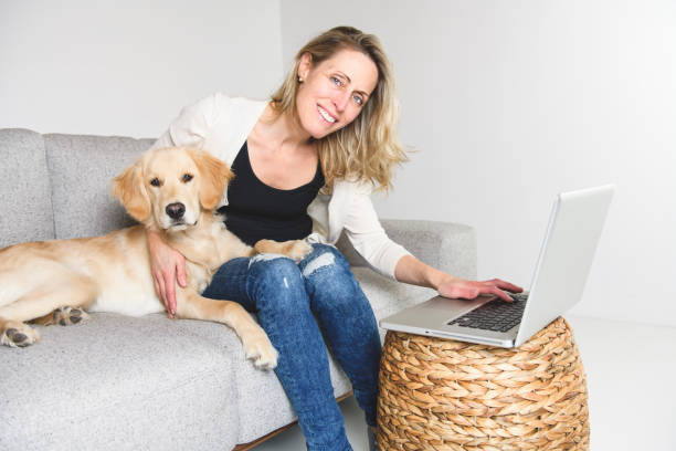 istock A woman with her golden Retriever dog using laptop on sofa 1210410047