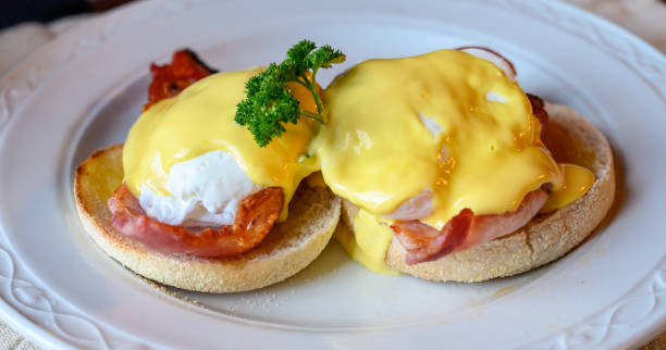 istock Weekend brunch in Scotland with two eggs benedict on homemade muffuns with roasted bacon and yellow hollandaise sauce. 1210410184