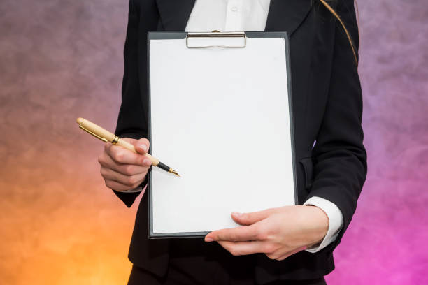 istock Beautiful woman with clipboard offering sign a contract with pen 1210413708