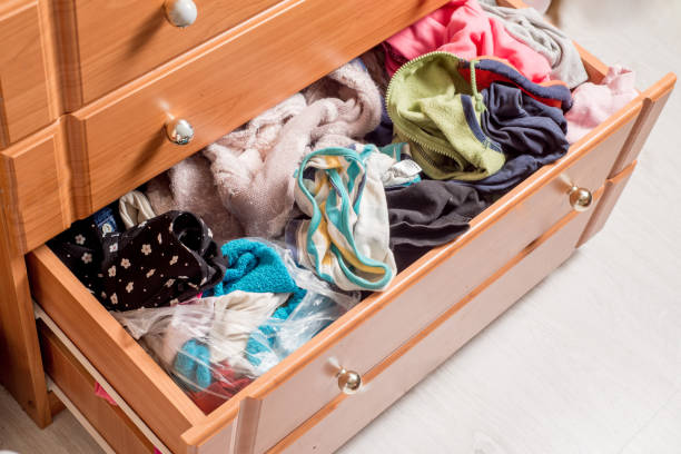 istock open chest drawers with sticking out randomly clothes.View from above 1210414076