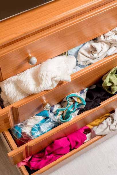 istock open chest drawers with sticking out randomly clothes.View from above 1210414080