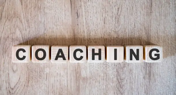 Photo of Coaching text word on wooden cubes on wooden background