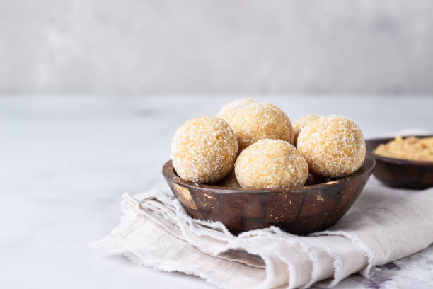 healthy vegetarian balls with chickpea, peanut butter and coconut in the wooden bowl. light grey background, selective focus. - oatmeal rolled oats oat raw imagens e fotografias de stock