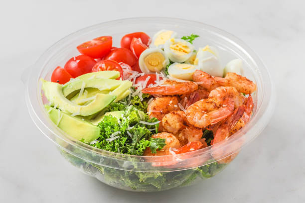 istock Healthy shrimp caesar salad with avocado, kale, tomatoes and eggs in plastic package for take away or food delivery 1210419604