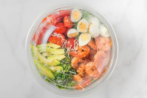 istock Plastic package with healthy shrimp caesar salad with avocado, kale, tomatoes and eggs to take away. mediterranean diet 1210419629