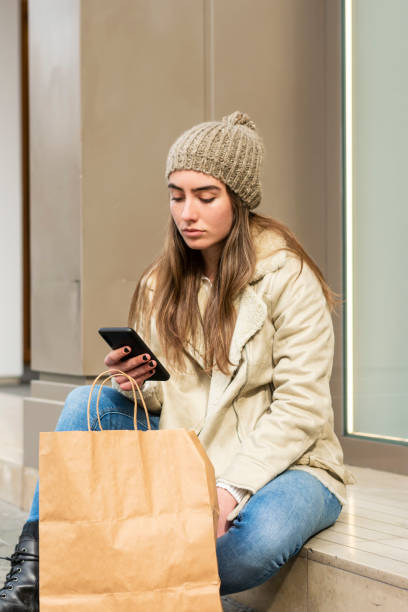 istock Cute woman sitting outdoors while using a phone 1210422233