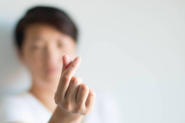 A person displays a love symbol from fingers in Korean style; selective focus at fingers. A woman making hand signs to be heart shape from the tip of thumb and index finger; meaning to tell love in Korean style called mini heart on a white background and selected focus at heart shape. pollex stock pictures, royalty-free photos & images