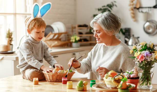 幸せなイースター!家族の祖母と耳を持つ子供は休日の準備をしています - grandmother senior adult family domestic kitchen ストックフォトと画像