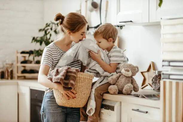 Happy family mother housewife and child son in laundry with washing machine