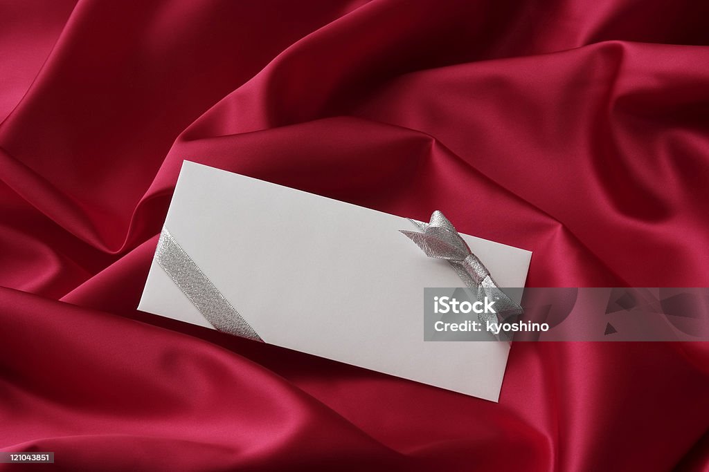 Decoração em branco, envelope com fita de prata sobre fundo de cetim vermelho - Foto de stock de Envelope royalty-free