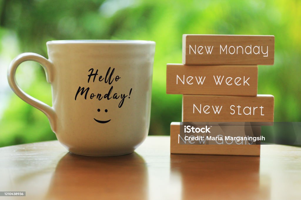 Monday concept with morning coffee cup - New Monday. New week. New start. New Goals. Hello Monday concept with inspirational motivational positive quote on wooden blocks - New Monday. New Week, New Start. New Goals. And a smiling face on a white morning cup of coffee or tea. Monday Stock Photo