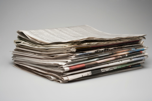 Stack of multiple sections of newspapers.