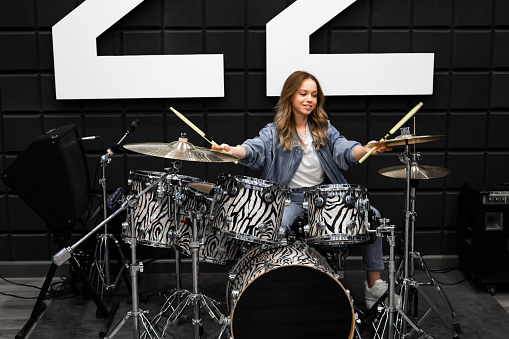 Creativity and music. Young beautiful girl plays the drums. Recording Studio. Musical equipment