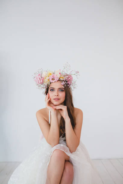 Portrait of beautiful bride with flower wreath on her head at white background stock photo