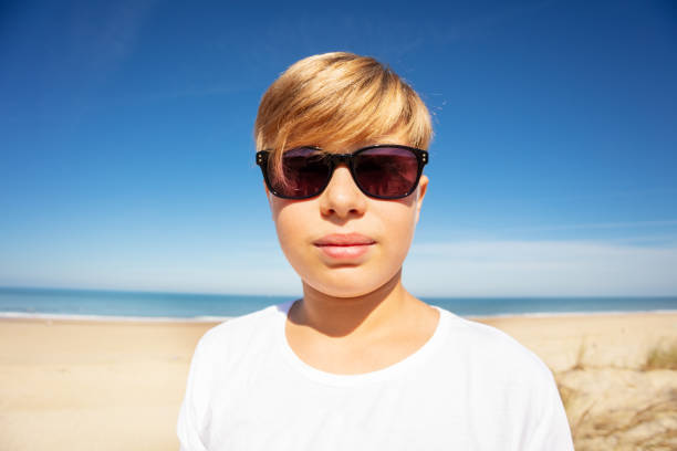 Close portrait of handsome boy in sunglasses on the beach