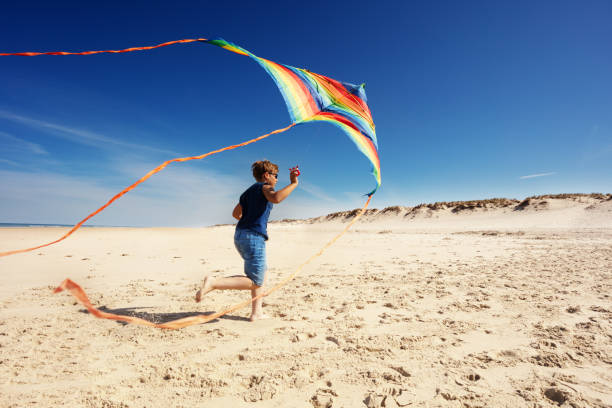 istock Boy run with color striped kite on the sand beach 1210442069