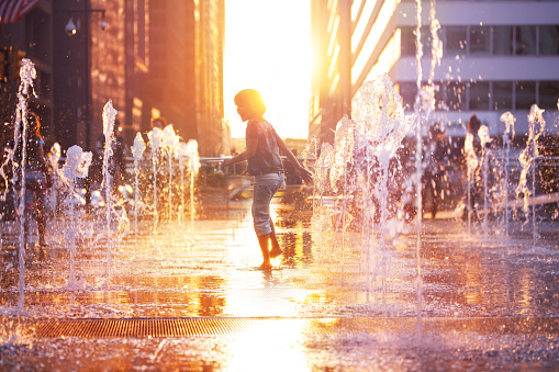 Child run and play on street fountain on Philadelphia square over sunset near city hall in downtown
