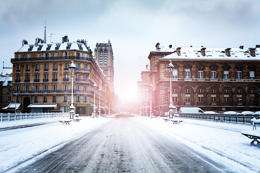 Road on Pont d'Arcole covered with snow at winter view in direction of Notre dame de Paris and cite