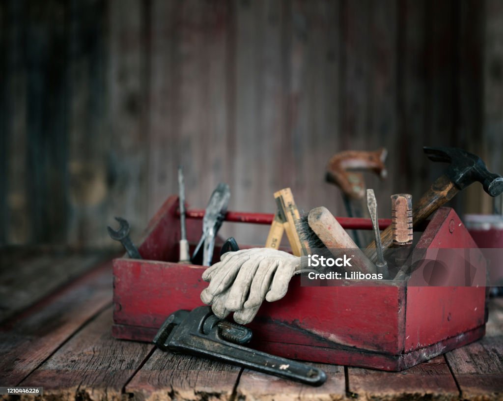 Antique Work Tools in a Toolbox Antique work tools in a red toolbox on an old wood background Toolbox Stock Photo