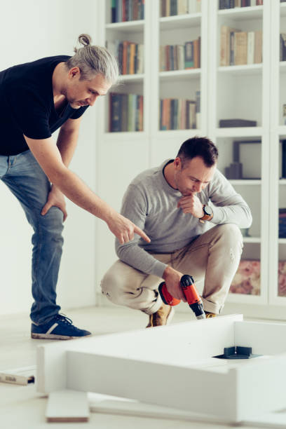 istock Mature man assembling furniture with his brother. 1210447409
