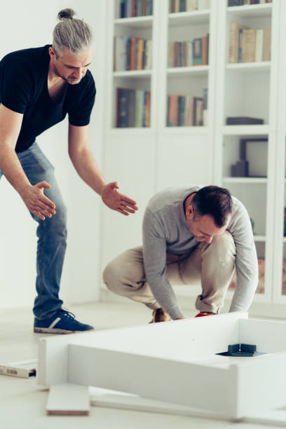 istock Mature man assembling furniture with his brother. 1210447942