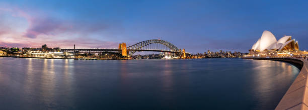 sydney harbor bridge e opera house panorâmica ao anoitecer em sydney, austrália - sydney australia sydney opera house australia sydney harbor - fotografias e filmes do acervo