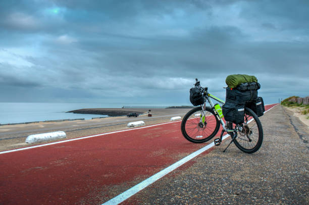 Modern bicycle on the road with backpack. Bike travel with bag along the seacoast, Netherlands