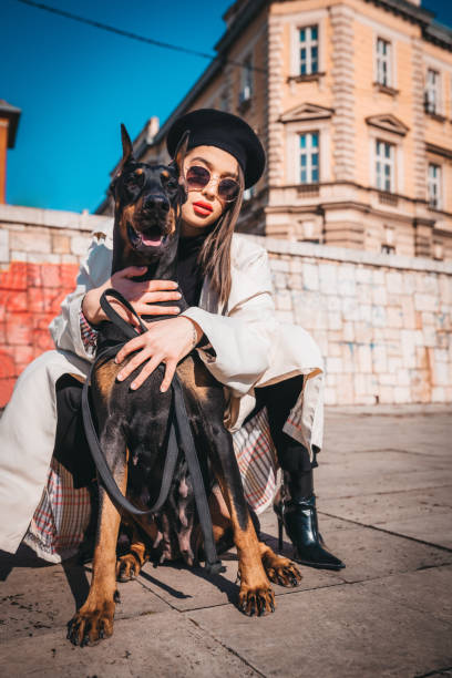 A young woman playing with her dog doberman