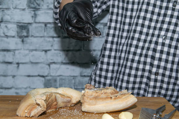 istock Woman's hand in a black glove sprinkles salt with lard 1210453176